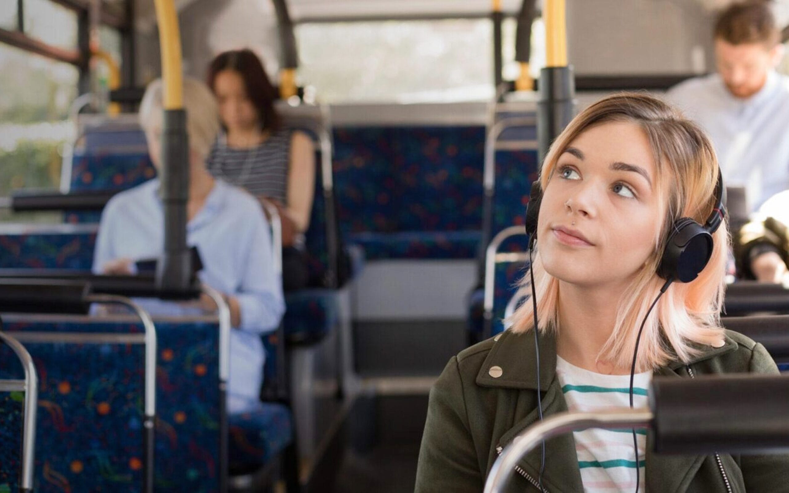 Kuvituskuva: Nainen kuuntelee audiota bussissa.